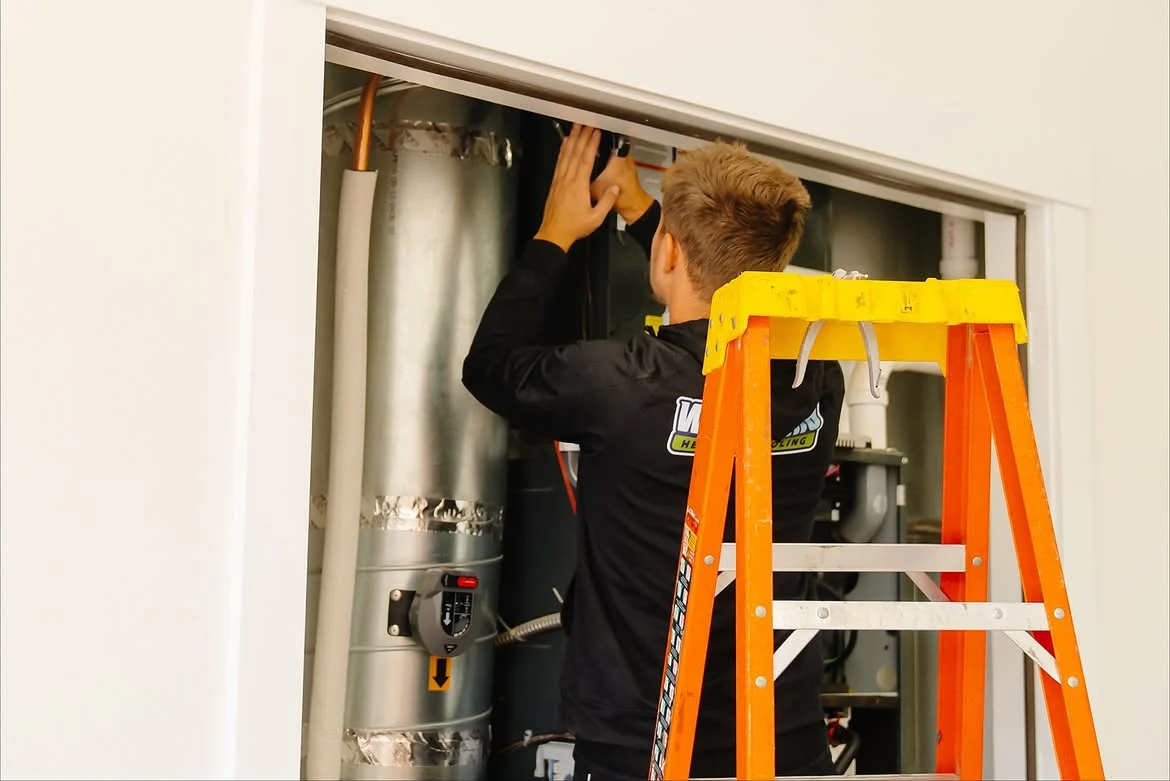 Whirlwind technician connecting ductwork above a furnace