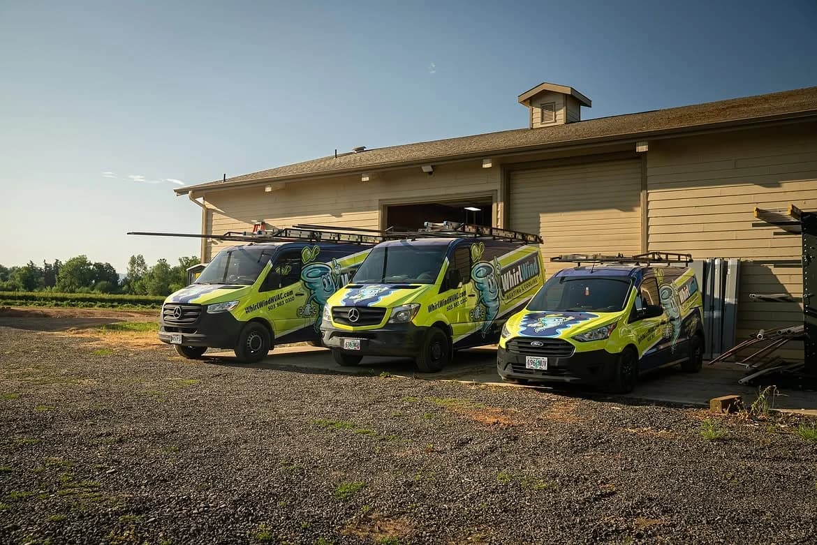 Three branded Whirlwind service vehicles parked outside the shop