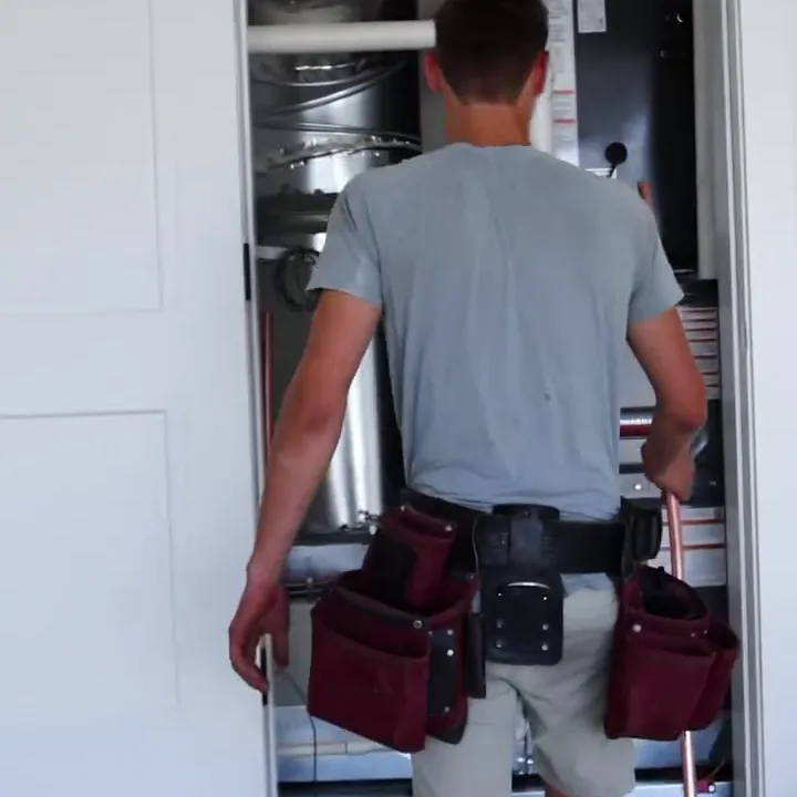 A technician working inside a ducted air handler closet