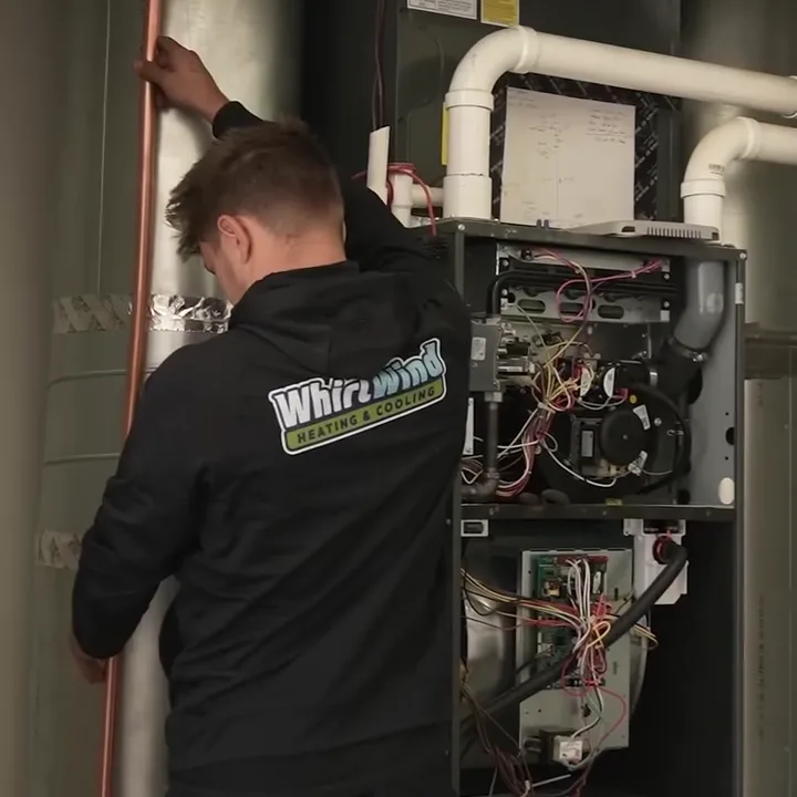 A Whirlwind technician in a branded hoodie working at an open furnace